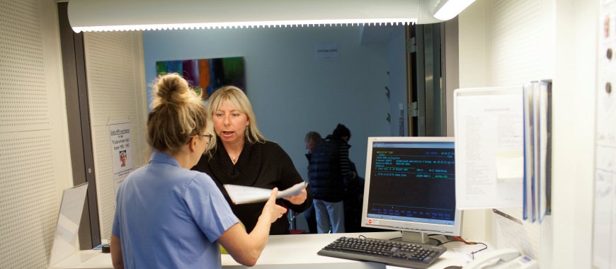 Sygeplejerske taler med patient henover skranken i Gynækologisk Klinik
