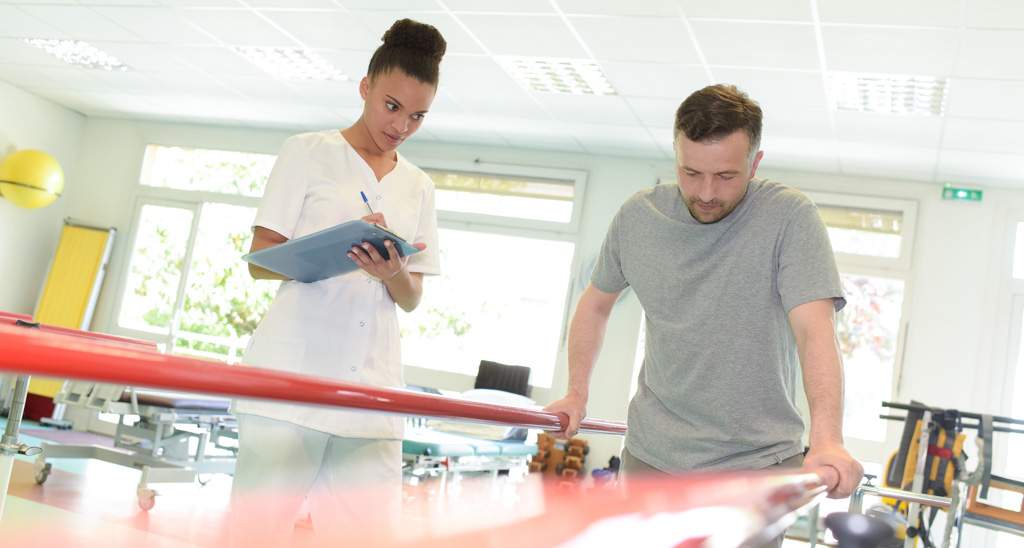 Billedet viser en fysioterapeut, som genoptræner en patient 
